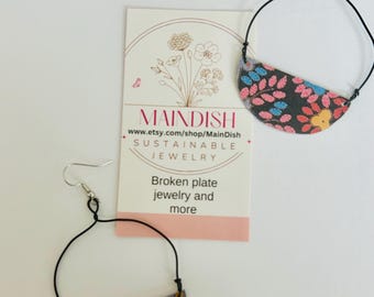 Pendientes llamativos de hojalata reciclada con diseño floral negro.