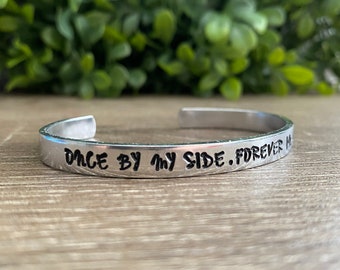 May include: Silver bracelet with the inscription "Once by my side. Forever in my heart."