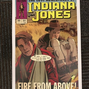 May include: A comic book cover featuring Indiana Jones in a red jacket and a man with a bandage on his arm. The cover is titled "The Lost Adventures of Indiana Jones: Fire From Above!" and features a plane in the background.