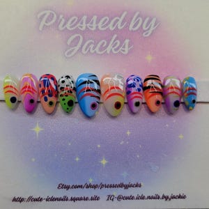 May include: A set of ten artificial nails with a variety of colorful designs. Each nail features a different pattern, including stripes, dots, and abstract shapes in shades of pink, blue, orange, and green. The nails are displayed on a white strip against a light purple background.
