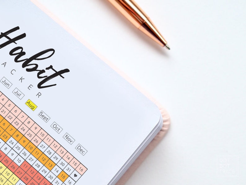 Pode incluir: Um rastreador de h&aacute;bitos com uma capa rosa e uma caneta dourada. O rastreador tem um layout de calend&aacute;rio com os meses de junho a dezembro. A palavra "Habit Tracker" est&aacute; escrita em preto no topo da p&aacute;gina.