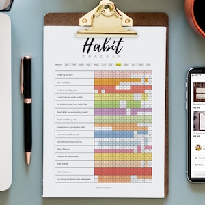 Puede incluir: Un planificador de h&aacute;bitos imprimible con una cuadr&iacute;cula colorida y una lista de h&aacute;bitos para realizar un seguimiento, como "Despertarse a la misma hora" y "Leer un libro". El planificador est&aacute; en un portapapeles con un clip dorado.