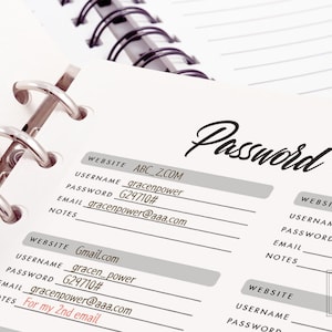 May include: A close-up of a password list written in a notebook. The notebook has a silver binder and the page is filled with handwritten website names, usernames, passwords, and email addresses. The text "Password List" is written at the top of the page.