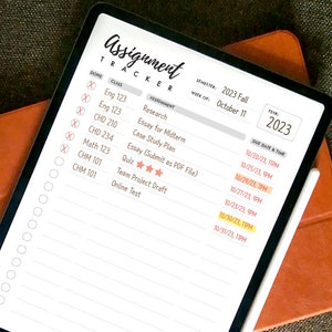 May include: A digital planner on a tablet screen with a white stylus. The planner is titled "Assignment Tracker" and includes a list of classes, assignments, due dates, and times. The semester is 2023 Fall and the week is October 11. The year is 2023.