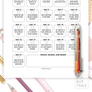May include: A white paper with a daily devotional plan, featuring numbered boxes with prompts for reflection and prayer. A multi-colored pen rests on the right side of the paper. The text includes phrases like "Reflect, Rejoice, and Renew."