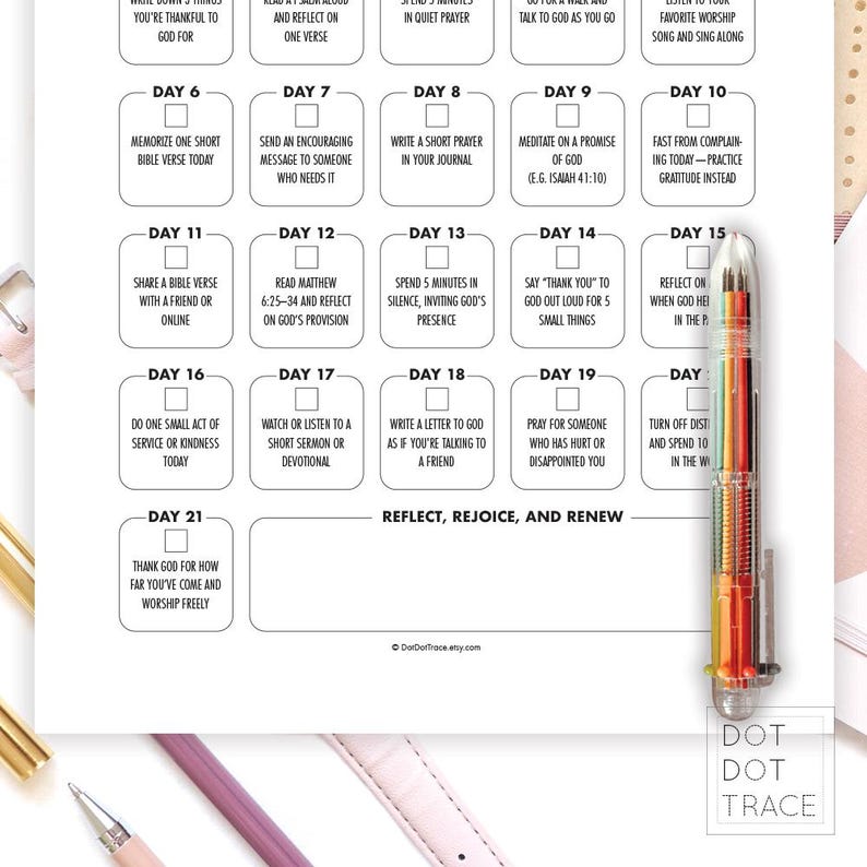 May include: A white paper with a daily devotional plan, featuring numbered boxes with prompts for reflection and prayer. A multi-colored pen rests on the right side of the paper. The text includes phrases like "Reflect, Rejoice, and Renew."