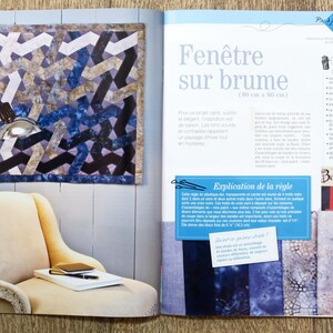 May include: A book page with a blue and gray quilt pattern on the left side of the page. The quilt is 30 inches by 30 inches. The right side of the page has text in French that says "Fen&ecirc;tre sur brume" which translates to "Window on the Fog". The text also says "(30 cm x 30 cm)".