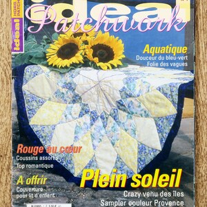 May include: The cover of "Ideal Patchwork" magazine, showcasing a patchwork quilt with yellow and blue designs, sunflowers, and French text. The cover includes the text "Plein Soleil" and "Aquatique".