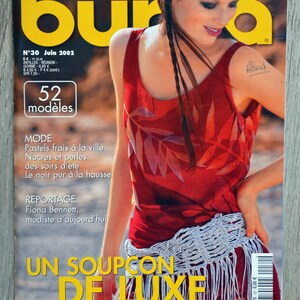 May include: A magazine cover featuring a woman wearing a red sleeveless top with a white crocheted belt. The magazine is titled "Burda" and the cover text reads "TENDANCES MODE" and "UN SOUPCON DE LUXE".