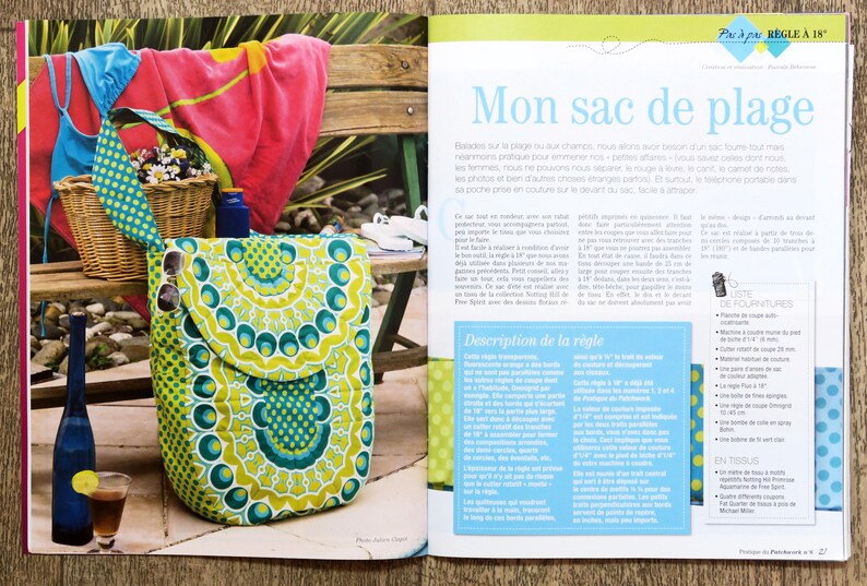 May include: A colorful, green and yellow patterned tote bag with a flap closure. The bag is sitting on a wooden surface with a magazine page in the background. The magazine page has the title "Mon sac de plage" and a description of the bag in French.