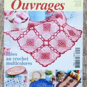 Puede incluir: La portada de la revista "Sabrina Tous les Ouvrages" presenta un tapete rojo tejido a ganchillo y el texto "Idées au crochet multicolores". También se ven un cuenco de macarons rosas y una taza azul.