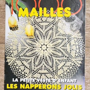 May include: A magazine cover with a cream-coloured crocheted doily as the central image. The title "1000 MAILLES" is in yellow. The cover also features the text "LA PETITE VESTE D'ENFANT LES NAPPERONS JOLIS". Two yellow tulips are visible.