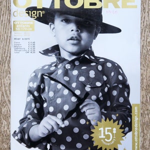May include: A magazine cover featuring a young person wearing a black and white polka dot shirt, a black fedora, and sunglasses. The magazine is titled "Ottobre design" and features the text "15th anniversary".