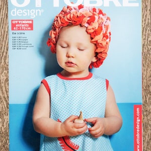 May include: The Ottobre Design magazine cover shows a child wearing a floral swim cap. The child is in a blue dress with red trim, holding a small object. The magazine text is in French, with the website www.ottobredesign.com.
