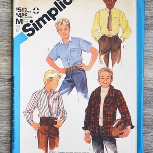 Può includere: Modello di cucito Simplicity numero 6563 per camicie da ragazzo. Il modello include tre diversi stili di camicie: una camicia blu a maniche corte, una camicia a righe a maniche lunghe e una camicia a quadri a maniche lunghe. Il modello include anche una tabella su come lavorare con i quadri.