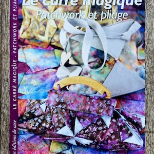 Può includere: Copertina del libro "Le carré magique Patchwork et pliage" con un tema patchwork. Mostra una borsa a mano con fantasia viola e marrone con manico in legno e una borsa tote colorata. È visibile anche il nome dell'autrice, Bernadette FAVRE.