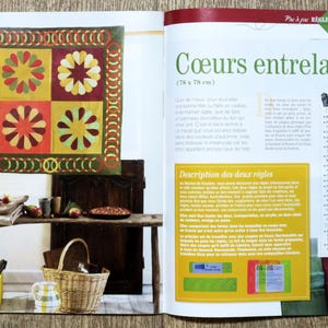 Op de afbeelding: Een tijdschriftpagina met een kleurrijk quiltpatroon met harten, getiteld "C&oelig;urs entrelac&eacute;s" (Frans voor "Verweven harten"). De pagina bevat ook een beschrijving van de quilt en instructies voor het maken ervan.