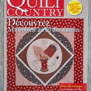 Op de afbeelding: Een tijdschriftcover voor Quilt Country, nummer 30, met een rood, bruin en wit quiltontwerp met een spoel garen en een hart. De tekst op de omslag luidt "Découvrez Ma bobine au fil des saisons" en "Nouvelle rubrique Les babioles de Béa Portrait Barbara Gendre".