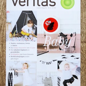 May include: A magazine cover with the title "veritas" in large white letters. The cover features images of babies and children's items, including a play tent, cribs, and a banner that says "OH BABY". The magazine's theme is baby and toddler related.