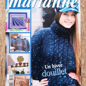 May include: Magazine cover featuring the title "les idées de marianne" in white and blue. The cover includes images of needlepoint projects, a woman wearing a blue knit sweater and hat, and the text "Un hiver douillet."
