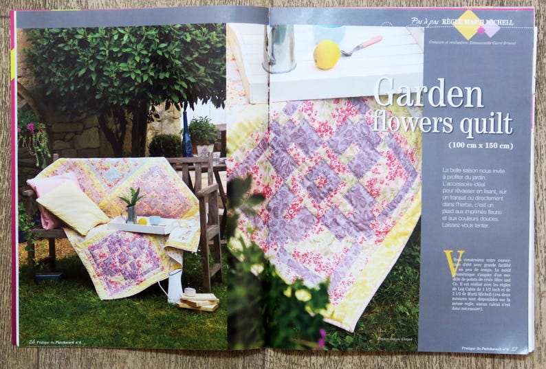 May include: A purple and white floral quilt with a yellow border. The quilt is displayed on a table with a white surface. The text "Garden flowers quilt (100 cm x 160 cm)" is printed on the page.