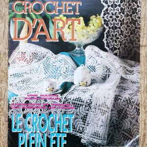 May include: A magazine cover with the title "TRICOT SELECTION CROCHET D'ART" in white and orange lettering. The cover features a white crocheted tablecloth, a glass bowl of grapes, and a teacup. The magazine's title is "LE CROCHET PLEIN ETE".