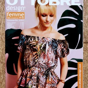 May include: The Ottobre Design magazine cover shows a woman in a tropical print off-the-shoulder top. The magazine's title and issue details are displayed at the top. Large, dark green leaf shapes form the background of the image.