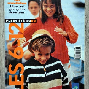 Puede incluir: Una portada de revista con dos niños, una niña con un suéter rojo y un niño con un suéter a rayas, con el título "LES 212" y "PLEIN ÉTÉ 2002" en letras grandes de color naranja. La portada de la revista también incluye el texto "30 modèles filles et garçons de 6 à 12 ans".