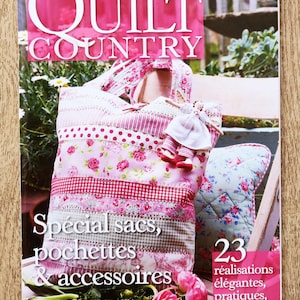 Peut inclure: La couverture du magazine "QUILT COUNTRY" présente un sac fourre-tout patchwork rose avec des motifs floraux et à pois. Le texte "Special sacs, pochettes & accessoires" est visible, ainsi qu'une petite poupée et un article matelassé. Le magazine affiche également le texte "23 réalisations élégantes, pratiques, tendance."