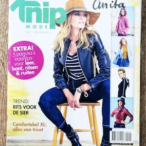 May include: A magazine cover featuring a woman wearing a black leather jacket, blue jeans, and a brown hat. The magazine is titled "Trip Mode" and the cover text says "Het grootste zelfmaakmodeblad van Nederland Anita".