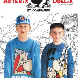 Peut inclure: Deux enfants portant des pulls bleus avec des images de bande dessinée d'Astérix et Obélix. Les pulls sont bleus avec des bordures blanches et présentent les visages des personnages. Le garçon à gauche porte une casquette de baseball bleue et blanche. Le garçon à droite porte une casquette de baseball noire. L'arrière-plan est un mur blanc avec un dessin en noir et blanc d'une scène de village.