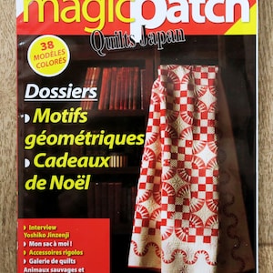 Puede incluir: Una portada de revista "magicpatch Quilts Japan" con texto en inglés y francés. La portada presenta un edredón rojo y blanco y una estantería en el fondo. La revista incluye artículos sobre patrones geométricos y regalos de Navidad.