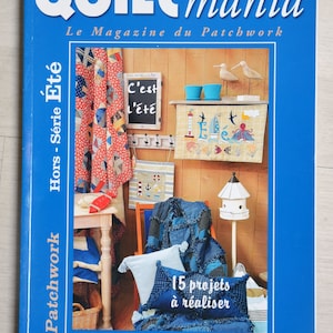 Op de afbeelding: Een blauwe magazinecover met de titel "Quilt mania" in witte letters. De cover toont een patchwork-thema met diverse knutselprojecten, waaronder quilts en decoratieve items. Tekst op de cover luidt "Le Magazine du Patchwork" en "15 projets à réaliser".