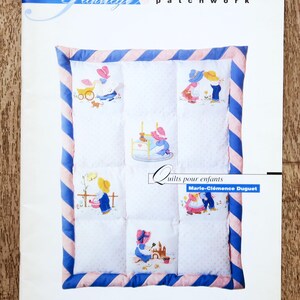 Könnte beinhalten: Ein Buchcover mit dem Titel "patchwork" und einem Quilt-Design. Der Quilt zeigt gestickte Szenen von spielenden Kindern, umrahmt von rosa und blau gestreiften Bordüren. Der Titel "Quilts für Kinder" ist ebenfalls sichtbar.