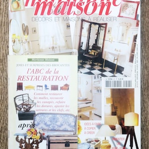 Op de afbeelding: Een tijdschriftcover met een Frans woonmagazine genaamd "Marianne Maison" met de tekst "Décors et Maisons à Réaliser" en een foto van een badkamer met een zwart-wit geblokte vloer. De tijdschriftcover toont ook een kleiner tijdschrift met de titel "l'ABC de la RESTAURATION" en een foto van een bank die wordt gerestaureerd.