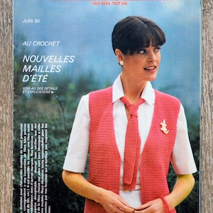 Könnte beinhalten: Ein Magazincover mit einer Frau, die eine rosa gehäkelte Weste mit einem weißen Hemd und einer Krawatte trägt. Das Magazin heißt "Tricot-Crochet" und der Text "Nouvelles Mailles d'été" ist sichtbar.