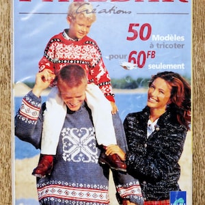 Könnte beinhalten: Magazin-Cover mit der Aufschrift "PHILDAR" und "50 Modelle zum Stricken". Das Cover zeigt eine Familie in Strickpullovern mit Wintermustern. Ein Junge sitzt auf den Schultern seines Vaters. Im Hintergrund eine Strandszene.