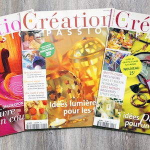 May include: Three French magazines titled "Création Passion" are displayed, featuring colourful covers with various themes. The magazines showcase articles on crafts, home decor, and seasonal projects, with text in French. The covers feature images of crafts and home decor.