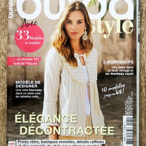May include: A magazine cover featuring a woman wearing a white and beige striped top with a ruffled neckline. The magazine is titled "burda style" and has the text "Avec 33 Modeles a coudre" and "Elegance Decontractee" on the cover.