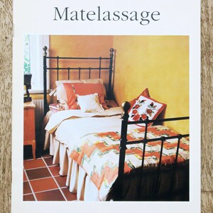 Peut inclure: Couverture de livre avec le titre "Matelassage" montrant une chambre avec un lit en métal noir. Le lit est orné d'une literie et d'oreillers à motifs orange et blancs. Les logos Husqvarna et Viking sont visibles.