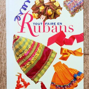 May include: A hardback book titled Tout Faire en Rubans with a white cover featuring a colourful collage of ribbon crafts, including a floral arrangement, a checkered hat, a bright orange skirt, and various loose ribbons and bows.