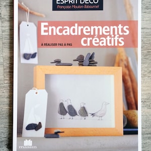 Op de afbeelding: Een boekomslag met een witte achtergrond en een houten frame. De titel van het boek is "Encadrements créatifs" en de ondertitel is "À réaliser pas à pas". Het boek gaat over creatieve inlijsttechnieken.