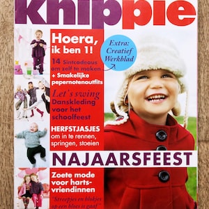 Op de afbeelding: Een Knippie tijdschriftomslag met een kind in een rode jas en een witte, pluizige muts. De omslag bevat teksten zoals Hoera, ik ben 1!, 14 Sintcadeaus, Let's swing, Herfstjasjes en Najaarsfeest, samen met kleine foto's van kinderen in diverse kleding.