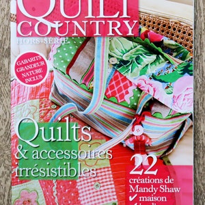Pode incluir: Uma capa de revista para Quilt Country, uma edição especial com 22 criações de quilts de Mandy Shaw. A capa apresenta uma bolsa de patchwork colorida com uma alça listrada e o texto "Quilts & accessoires irrésistibles".