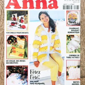 May include: A magazine cover titled "Anna" with a woman wearing a yellow and white outfit. The cover includes text in French, such as "Fêtez l'été!" and images of crafts, including ladybugs, roses, and table runners.