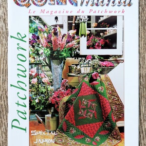 Peut inclure: Couverture du magazine Quiltmania avec un quilt patchwork vert et rouge à motifs floraux. Le magazine est intitulé "Quiltmania" et "Le Magazine du Patchwork". La couverture présente également une étiquette d'édition spéciale qui dit "Special Japon".