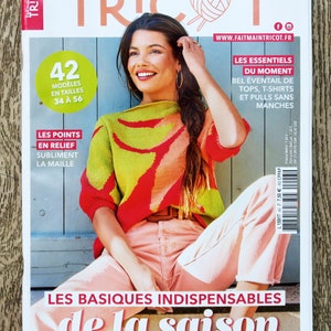 Puede incluir: Una portada de revista con una mujer que lleva un suéter de punto de colores. La revista se titula "Fait main TRICOT" y presenta los textos "Les essentiels du moment" y "Les basiques indispensables de la saison".