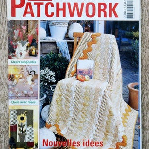 Puede incluir: Una portada de revista para Sabrina Patchwork, que presenta una colcha con un patrón floral amarillo y blanco. La colcha está drapeada sobre una silla con un libro y manzanas encima. El texto de la portada dice "Nouvelles idées simples et créatives".