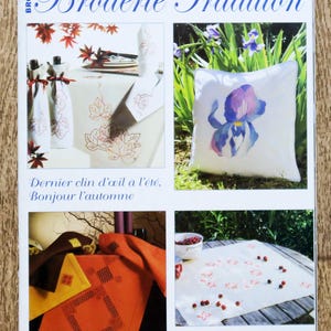 Peut inclure: Couverture du magazine "Broderie Tradition" présentant des projets de broderie. La couverture comprend des images d'articles brodés comme un coussin avec un motif floral, des nappes et des bouteilles décoratives. Le texte comprend "Septembre 2009 - N 11" et des phrases en français.