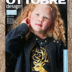 May include: The Ottobre Design magazine cover shows a young girl with blonde curly hair. She wears a dark grey jacket with gold studs and a gold zip. The magazine title is in large white letters. The cover also includes text about the magazine's contents.